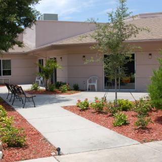 A well-maintained building exterior with a landscaped garden and benches along a sidewalk.