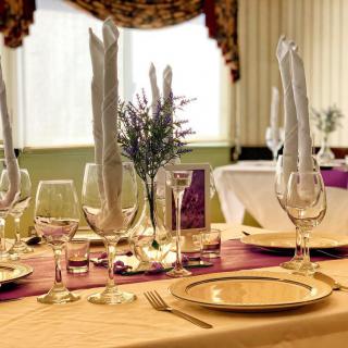 An elegant dining table set with plates, wine glasses, and folded napkins in a refined restaurant setting.