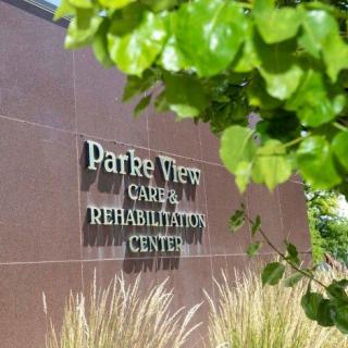 Parke View Care and Rehabilitation Center sign surrounded by trees and plants.