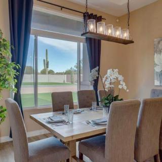 A well-decorated dining room with a wooden table, upholstered chairs, and a modern chandelier.