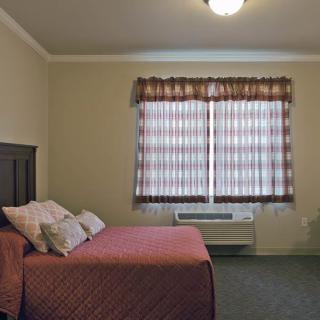 A cozy bedroom with a neatly made bed and patterned curtains by the window.