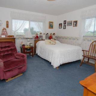 A cozy and inviting bedroom with a white bed, plush seating, and personal touches.