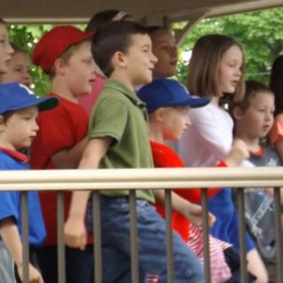 A group of children performing outdoors on a stage.