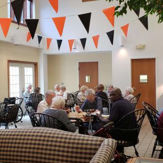 A group of people socializing in a cafe decorated with orange and black bunting.