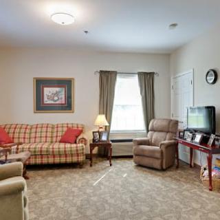 A cozy living room with a sofa, armchair, and a television.