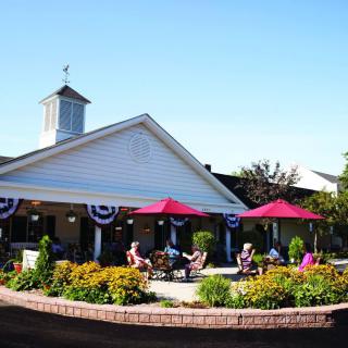 A charming outdoor patio area with red umbrellas and people enjoying a sunny day.