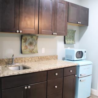 A cozy kitchen featuring dark cabinets, a granite countertop, and a charming blue microwave.