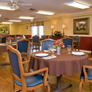 A well-decorated dining room with neatly arranged tables and chairs, adorned with paintings on the walls.