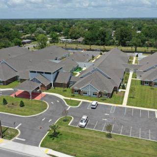 Aerial view of a building complex with parking lots and surrounding greenery.