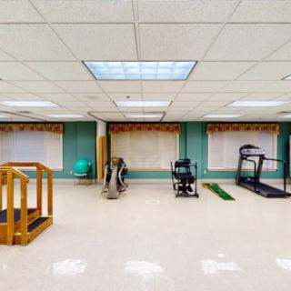 An indoor gym with various exercise equipment including a treadmill and physical therapy tools.
