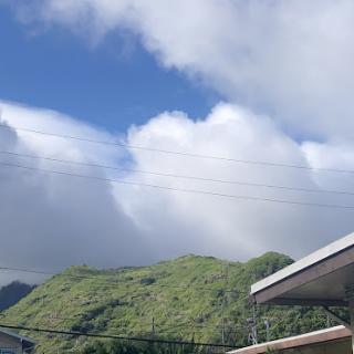 A serene view of green mountains under a partly cloudy sky.
