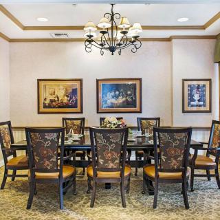 A formal dining room with a large table surrounded by chairs and decorated with artwork and a chandelier.