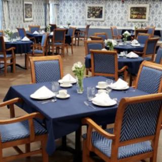 A neatly arranged dining area with blue tablecloths and wooden chairs.