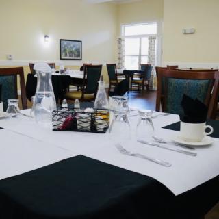 An elegantly set dining table in a restaurant with black and white tablecloths and neatly arranged cutlery.