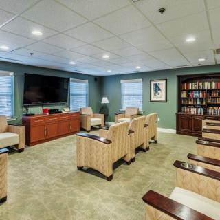 A cozy room with comfortable seating, a large television, and a bookshelf.