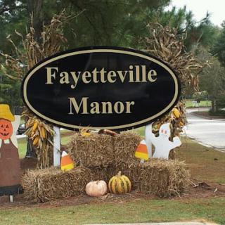 Festive Halloween decorations at Fayetteville Manor, featuring pumpkins, hay bales, and ghost figures.
