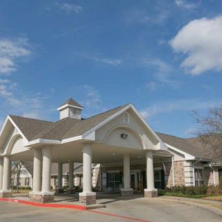 A building with a prominent entrance featuring columns and a pointed roof under a blue sky.