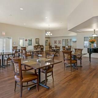 A well-lit dining area with several tables and chairs arranged on a wooden floor.