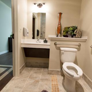 A modern, accessible bathroom with a sink, mirror, and toilet.