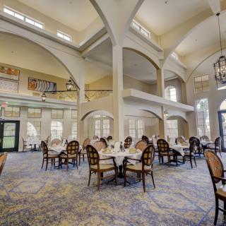 A spacious and elegant dining area with high ceilings and neatly arranged tables and chairs.