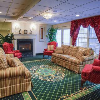 A traditionally decorated living room featuring a fireplace, patterned sofas, and elegant curtains.