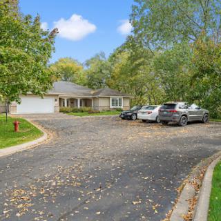 A peaceful suburban home with a spacious driveway surrounded by lush greenery.