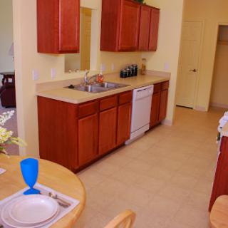 A cozy kitchen with wooden cabinets and a dining area, featuring modern appliances.