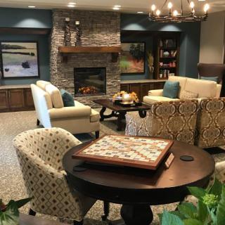 A cozy living room with a stone fireplace, comfortable seating, and a coffee table featuring a game board.
