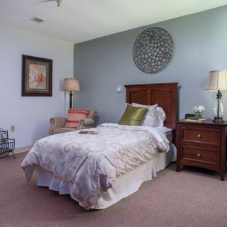 A cozy bedroom with a wooden bed, decorative pillows, and matching nightstands, accented by lamps and wall art.