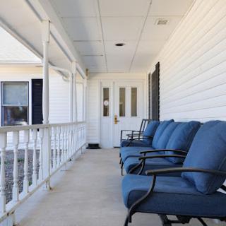 A cozy porch featuring comfortable seating with blue cushions and a welcoming entrance.