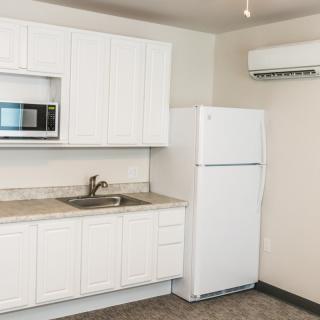 A modern kitchen with white cabinets, a refrigerator, microwave, and sink.