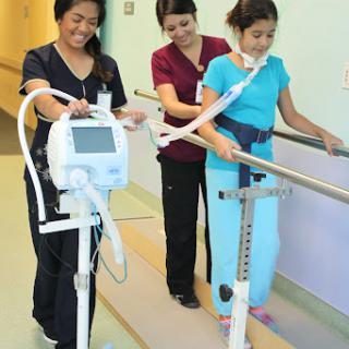 Healthcare professionals assisting a patient during physical therapy to improve mobility.