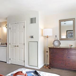 A cozy bedroom featuring a wooden dresser with a mirror above, accompanied by a modern lamp.
