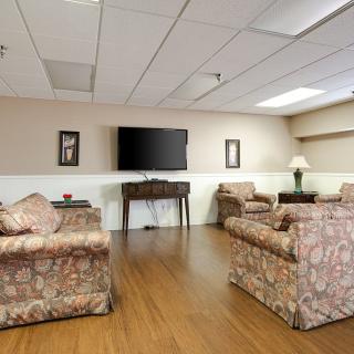 A cozy living room with patterned sofas and a flat-screen TV mounted on the wall.