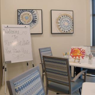 A meeting room with a whiteboard, chairs, and decorative artwork on the walls.