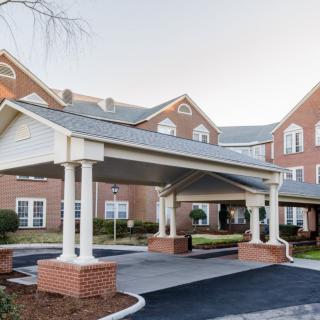 A brick building with a covered entrance and multiple windows, showcasing residential architecture.