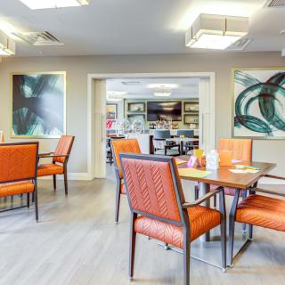A modern dining room with orange chairs and contemporary artwork on the walls.