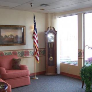 A cozy living room with a grandfather clock, an American flag, and a comfortable sofa.