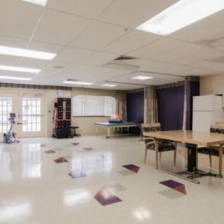 A spacious community recreation room with tables, chairs, and a ping pong table.