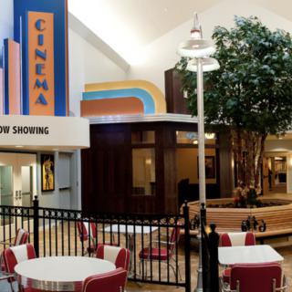A retro-themed cinema entrance inside a mall, featuring tables and chairs in the seating area.