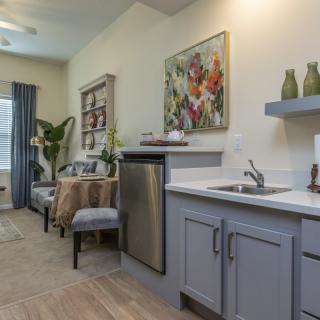 A modern apartment kitchen with a cozy dining area and colorful artwork on the wall.