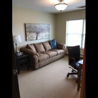A cozy living room with a sofa, desk chair, and window providing natural light.