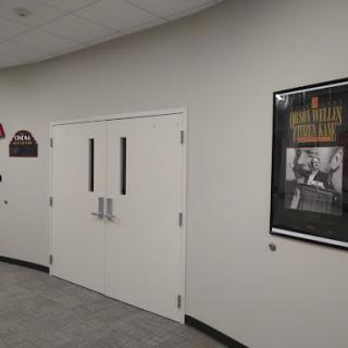 A view of a hallway featuring a pair of doors and a framed poster on the wall.