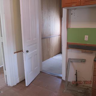 An unfinished interior space with a partially open door leading to another room.