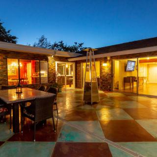 A modern outdoor patio with warm lighting, featuring furniture and a cozy atmosphere during the evening.