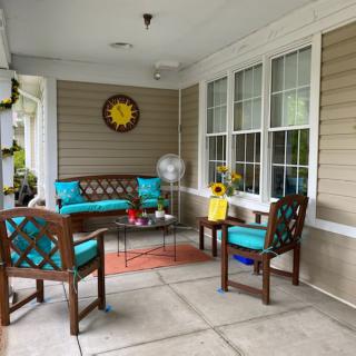 A cozy porch with vibrant teal-cushioned furniture and cheerful decor.