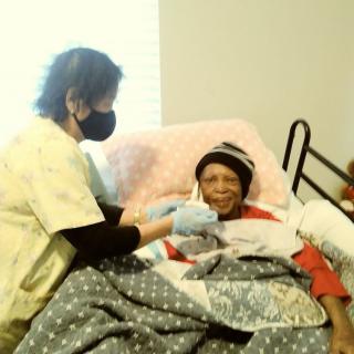 A nurse providing care to an elderly patient in a hospital bed.