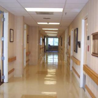 A clean and empty hospital corridor with open doors and bright lighting.