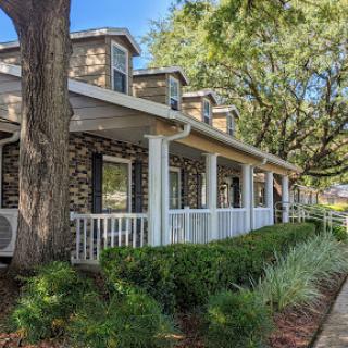 A charming house featuring a welcoming porch and lush greenery.