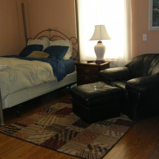Cozy bedroom with a bed, lamp, chair, and rug.